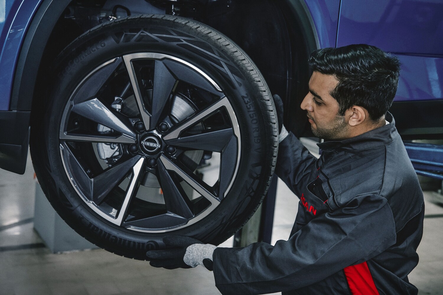 Nissan yetkili servisinde Qashqai bakımı yapılırken teknisyen jant ve lastik kontrolü yapıyor
