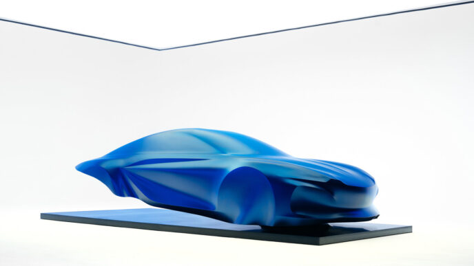 Yeni Alpine A110'un tasarımını önizleyen mavi örtülü heykel, ön 3/4 görünüm
